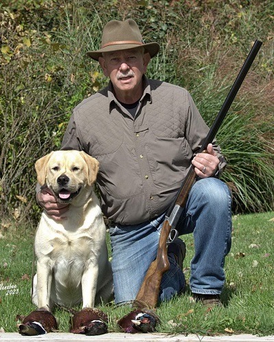 A man with his yellow Labrador after a successful bird hunt